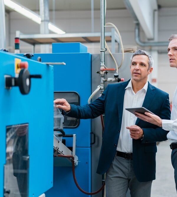 Two,Businessmen,With,Tablet,Talking,In,A,Factory